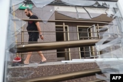 A man walks past a broken window in a residential building damaged as a result of a missile being shot down during a night strike in Odesa, July 19, 2023. Russia launched strikes on Ukraine's southern Odesa region, the local governor said.