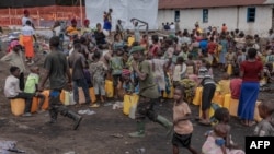 Congolese army soldiers walk among the displaced Congolese women and children at the Bulengo camp a few kilometers from the center of Goma, eastern Democratic Republic of Congo, on Feb. 16, 2024. 