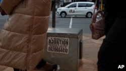 Women pass a sticker advertising abortion pills on a sidewalk in Johannesburg, South Africa, on June 28, 2023. Abortion policy and availability are among the issues that could be affected by the winner of the Nov. 5, 2024, U.S. presidential election.