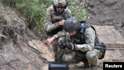 Pripadnik plaćeničke grupe Vagner i beloruski vojnik učestvuju u zajedničkoj obuci u vojnom kampu Brest, u Belorusiji, nedaleko od granice sa Poljskom, 20. jula 2022.