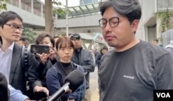 社民连内务副主席余炜彬接受传媒访问时，有便衣警察在后方近距离拍摄 (美国之音/汤惠芸)