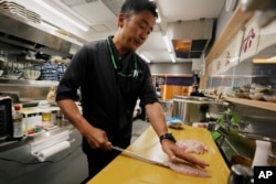 Katsumasa Okawa, owner of a fish store and a restaurant, cuts flounder meat as he prepares at his restaurant in Iwaki, northeastern Japan, July 13, 2023.