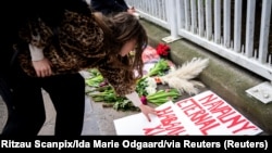 A woman places a poster in front of the Russian embassy as people gather following the death of Russian opposition leader Alexey Navalny in Copenhagen, Denmark, Feb. 16, 2024. (Ritzau Scanpix/Ida Marie Odgaard)