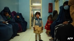 FILE - A child stands in a waiting room at a clinic run by the Swedish Committee for Afghanistan, in Wardak province, Afghanistan, Oct. 6, 2021. The SCA was forced to halt its activities last year, including services for new mothers and support programs for the disabled. 