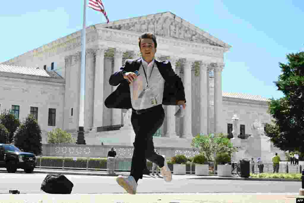 A journalist runs across the U.S. Supreme Court plaza carrying an opinion to a news correspondent as the court handed down decisions, in Washington. Former President Donald Trump hailed a "big win" for democracy after the Supreme Court ruled that presidents have presumptive immunity for official acts -- a decision set to delay his trial for conspiring to overturn his 2020 election loss.