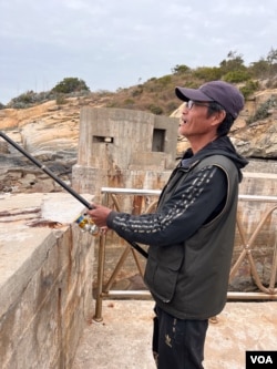 Retired bag designer Ouyang Cheng-yi fishes on top of a military tunnel-turned-tourist attraction in Kinmen on Jan. 17, 2024. The tunnel was originally built to hide military boats. (Elizabeth Lee/VOA)