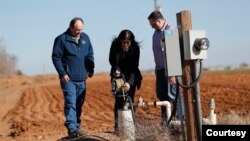 Texas Tribune reporter Jayme Lozano checks out an e-line water level meter attached to a water well near the High Plains Underground Water Conservation office in Lubbock, Texas, in December of 2023. (Mark Rogers/Texas Tribune)