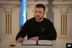 Arhiva - Ukrajinski predsednik Volodimir Zelenski potpisuje bezbedsmo sporazum između Ukrajine i Britanije, u Kijevu, 12. januara 2024.