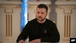 FILE - Ukrainian President Volodymyr Zelenskyy signs a document in Kyiv, Jan. 12, 2024.