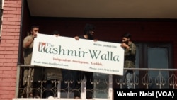 Staff at The Kashmir Walla remove the media outlet's sign from their former office in Srinagar, Indian-administered Kashmir, on Aug. 21, 2023. (Wasim Nabi/VOA)