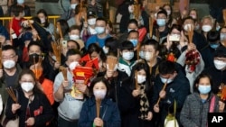 FILE - Worshippers wait to burn joss sticks at the Wong Tai Sin Temple, Jan. 21, 2023, in Hong Kong, to celebrate the Lunar New Year. The mask mandate has since been lifted, but most Hong Kongers continue to wear the coverings.