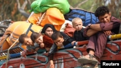 Afghan refugee children sit on a truck loaded with belongings as they and their families prepare to return home, outside the United Nations High Commissioner for Refugees repatriation centers in Azakhel town in Nowshera, Pakistan, Oct. 30, 2023.