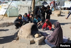 A Palestinian woman bakes bread as children sit next to her, while Gaza residents face crisis levels of hunger and soaring malnutrition, in Khan Younis in the southern Gaza Strip, Jan. 24, 2024.