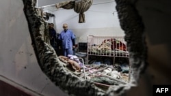 FILE - People inspect the damage in a room following Israeli bombardment at Nasser hospital in Khan Yunis in the southern Gaza Strip on Dec. 17, 2023.