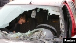 FILE - Seorang warga setempat memeriksa mobil rusak yang terkena tembakan, yang oleh pemerintah setempat disebut sebagai serangan militer Ukraina, di pemukiman Razumnoe di wilayah Belgorod, Rusia 19 Maret 2024.