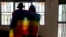 FILE - A gay Ugandan couple cover themselves with a pride flag as they pose for a photograph in Uganda, March 25, 2023.