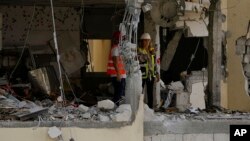 Radnici utvrđuju štetu na stambenoj zgradi oštećenoj u raketnoj vatri iz Pojasa Gaze, u Rehovotu, Izrael, 12. maja 2023.