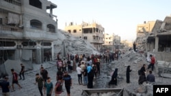 Palestinci se okupljaju da provere zgradu ubrzo pošto je srušena izraelskim bombardovanjem u izbegličkom kampu Nuseirat u centralnom pojasu Gaze, 22. avgusta 2024.