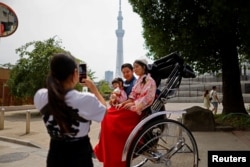 Rickshaw puller Akina Suzuki, 19, takes a photo of a family of tourists from Taiwan during her guided tour around the Asakusa district in Tokyo, Japan, June 18, 2023. (REUTERS/Issei Kato)