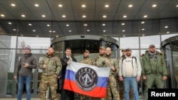 FILE - Visitors pose outside PMC Wagner Center, which is a project implemented by the founder of the Wagner private military group, Yevgeny Prigozhin, during the official opening of the office block in Saint Petersburg, Russia, Nov. 4, 2022. 