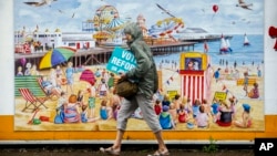 A woman carries electoral leaflets for Nigel Farage's Reform UK Party in Clacton-on-Sea, England, July 2, 2024. 