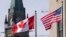 FILE - The Canadian and US flags are displayed on lampposts March 22, 2023, near Parliament Hill in Ottawa, Ontario. 