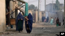 FILE - Burqa-clad Afghan women walk on a street in a neighborhood where mostly Afghan populations live, in Karachi, Pakistan, Jan. 26, 2024. 