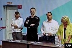 A screen shows the already imprisoned Russian opposition figure Alexey Navalny, 2nd left, as he listens to his verdict at the IK-6 penal colony, a maximum-security prison, in the settlement of Melekhovo in the Vladimir region, Aug. 4, 2023.