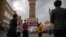 FILE - Tourists take photos near a tower at the International Grand Bazaar in Urumqi in western China's Xinjiang Uyghur Autonomous Region, as seen during a government-organized trip for foreign journalists on April 21, 2021.