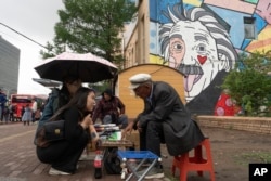 A Mongolian woman consults a fortuneteller divining fortunes with stones on a street across from Sukhbaatar Square in Ulaanbaatar, Mongolia, on June 27, 2024.