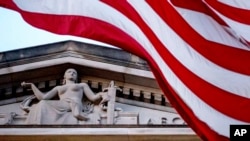 FILE - An American flag flies outside the Department of Justice building in Washington, March 22, 2019. Public confidence in American institutions has dropped, according to a new Gallup analysis.