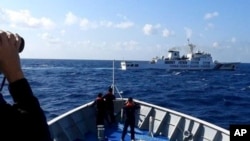 资料照：菲律宾海岸警卫队发布照片显示，一艘中国海警船（上）正在有争议的南中国海阻拦一艘菲律宾政府船只登陆铁线礁（Sandy Cay ）。（2024年3月21日）