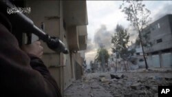 FILE - In this image from video released by Hamas on Dec. 2, 2023, a Hamas fighter aims an Al-Yasin rocket at an Israeli armored vehicle in Beit Hanoun, Gaza.