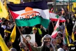 A supporter of the Iranian-backed Hezbollah group waves a Palestinian flag with Arabic words that read: "Jerusalem we are coming," during a rally in Beirut, Lebanon, Nov. 3, 2023.