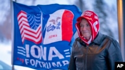 FILE - A man stands next to a flag that reading "Iowa for Trump" in Urbandale, Iowa, Jan. 11, 2024. Voters in the state are participating in caucuses on Jan. 15, 2024, that launch the Republican presidential nomination process.