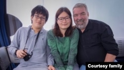 Emily Chen, flanked by her son and husband, Mark Lent, takes the Victoria Peak tram in Hong Kong in 2018. Chen was detained by Chinese authorities on Dec. 29, 2023, and has been held since then on charges of spying. (Photo courtesy of Mark Lent)