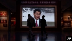 Visitors pass a video screen showing Chinese President Xi Jinping at the museum of the Communist Party of China in Beijing, Oct. 19, 2023.