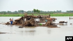 FILE - Villagers search for their belongings after their huts were destroyed in flood waters in Jaffarabad district of Balochistan province, Pakistan, Aug. 22, 2022.
