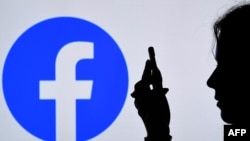 FILE - In this photo illustration, a person looks at a smartphone with a Facebook App logo displayed on the background, on Aug. 17, 2021, in Arlington, Virginia. 