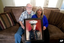 FILE - Joey and Paula Reed pose for a photo with a portrait of their son Marine veteran and Russian prisoner Trevor Reed at their home in Fort Worth, Texas, Feb. 15, 2022.