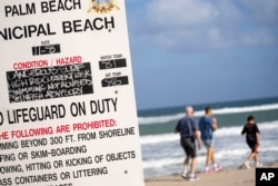 Warnings about dangerous surf and strong currents are posted on the beach in Palm Beach, Fla., Tuesday, Nov. 8, 2022, as Tropical Storm Nicole continues to increase in strength and is expected to make landfall along Florida's east coast early Thursday.