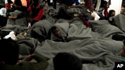 Migrants are wrapped with blankets as they gather on the deck of the Ocean Viking rescue ship, in the Strait of Sicily, in the Mediterranean Sea, Nov. 4, 2022.