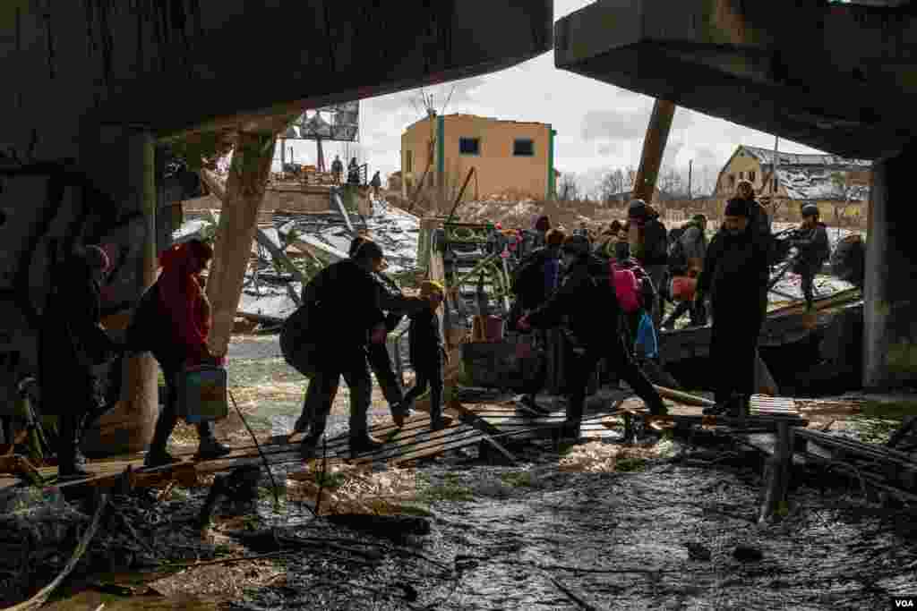 Women, children and the elderly had to go through the Irpin River after the bridge that links Kyiv to this small town was bombed by Ukrainian forces as a strategy to slow down the Russian troops' advance, in Irpin, Ukraine, March 8, 2022. (Yan Boechat/VOA