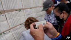People check a voter list to confirm where they should cast their ballots during legislative elections in Bogota, Colombia, Sunday, March 13, 2022. (AP Photo/Fernando Vergara)