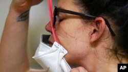 Arhiva, ilustracija - Žena skida zaštitnu masku tokom pamdenije Kovida 19.