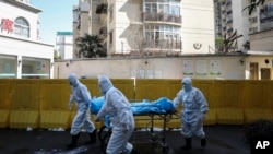 Medical workers move a person who died from COVID-19 at a hospital in Wuhan in central China's Hubei province, Feb. 16, 2020.