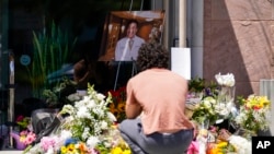 Gabe Kipers, a neighbor of church shooting victim Dr. John Cheng, kneels at a memorial for him outside his office building on May 17, 2022, in Aliso Viejo, Calif. 