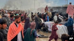 People gather beside a burnt truck destroyed by Afghan shelling, in Chaman, a town in Pakistan's southwest near Afghan border, Dec. 11, 2022.