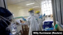 Isyarat petugas kesehatan yang mengenakan APD di ruang isolasi pasien COVID-19 usai pengambilan sampel usap, di IGD RS Persahabatan, Jakarta, 13 Mei 2020. (Foto: REUTERS/Willy Kurniawan)
