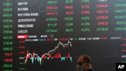 资料照 - 2020年2月14日，一位戴着口罩的男子走过上海股票交易大楼前显示股票走势的巨大电子屏幕。